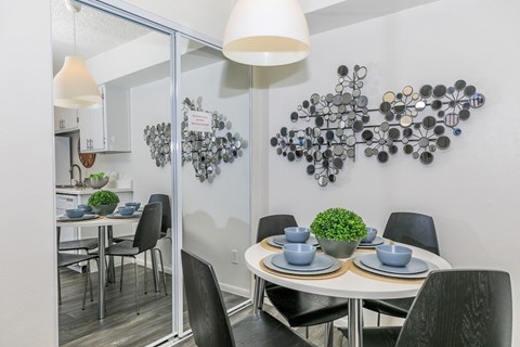 A dining room with a white table and black chairs.