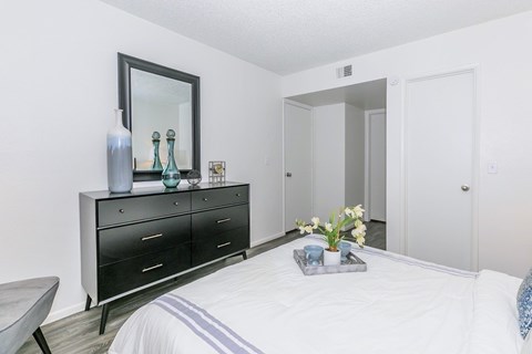 A bedroom with a black dresser and a mirror above it.