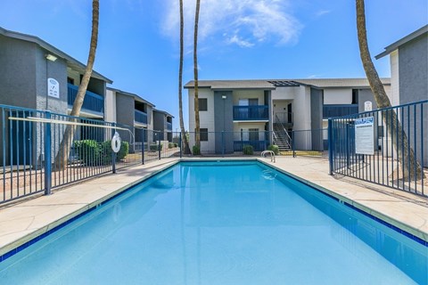 A swimming pool in front of a row of apartment buildings.