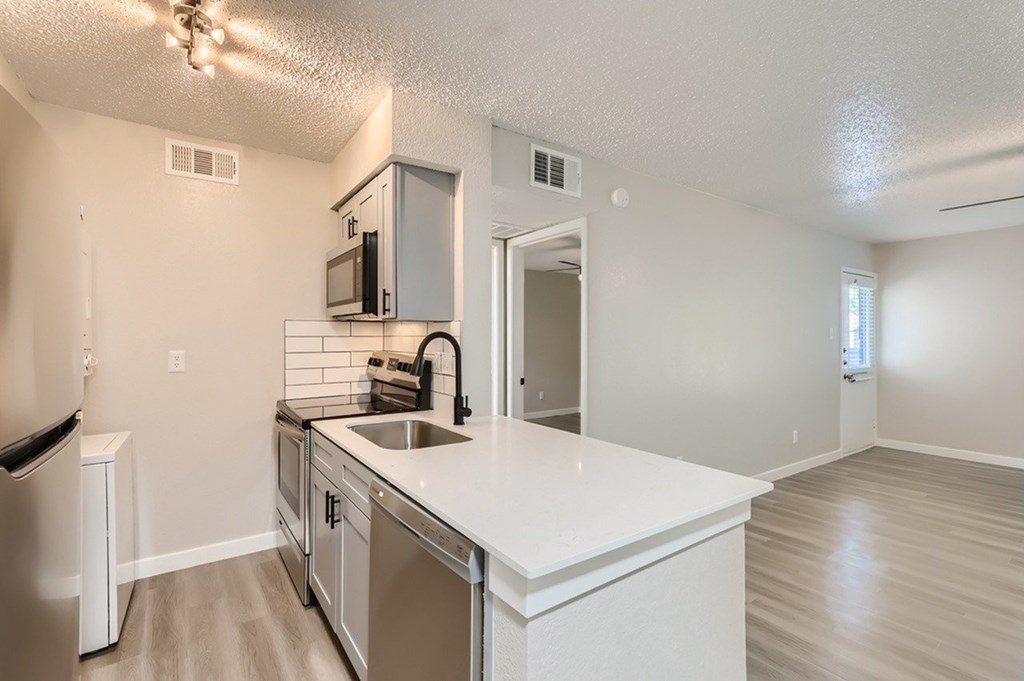 A kitchen with white countertops and stainless steel appliances.