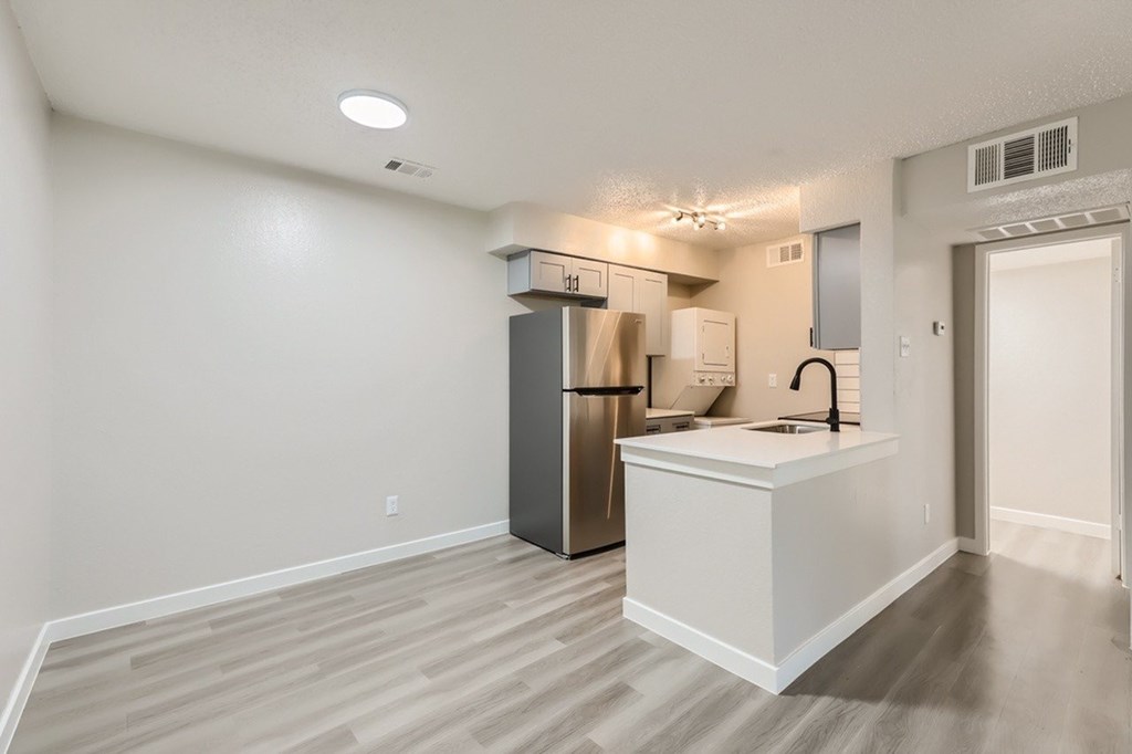 A kitchen with a refrigerator, sink, and cabinets.
