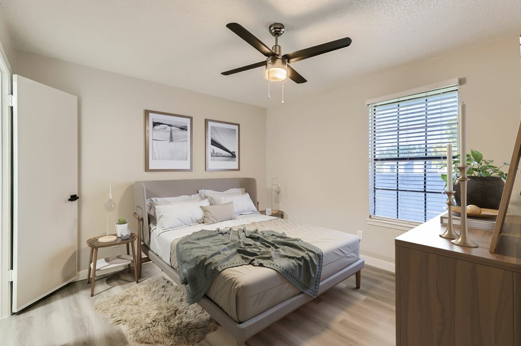 A bedroom with a bed, a ceiling fan, and a window with blinds.