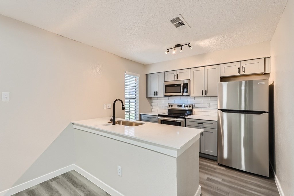 A kitchen with a stainless steel refrigerator and a white countertop.