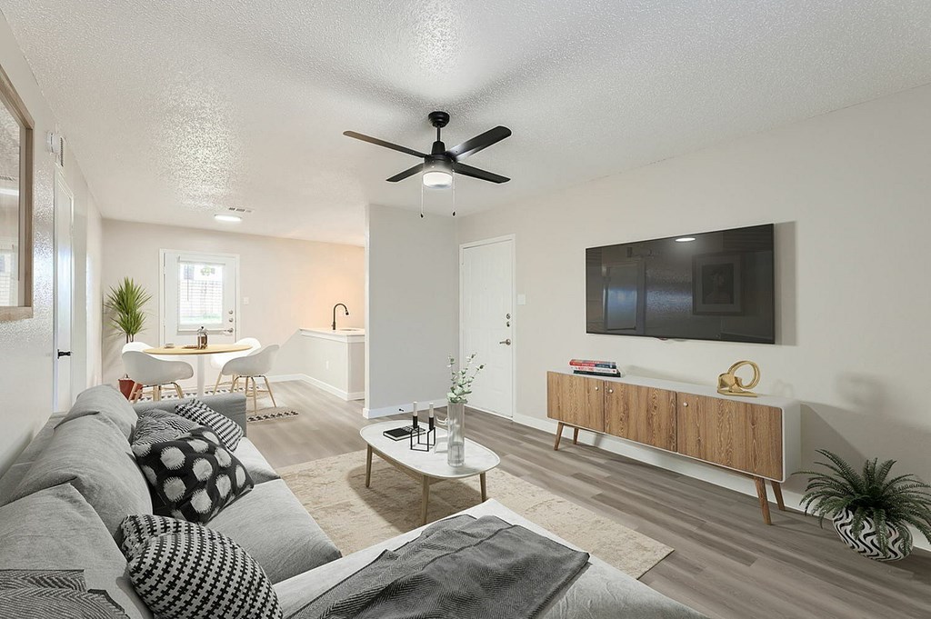 A living room with a grey couch and a ceiling fan.