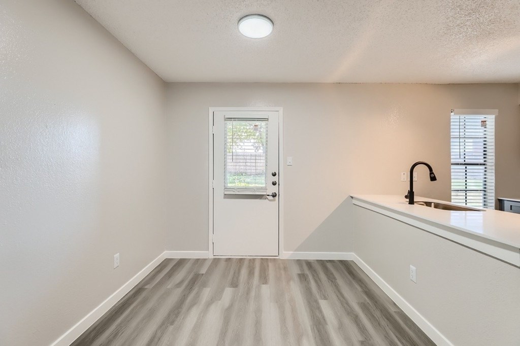 A white door with a window above it in a room with light wood flooring.