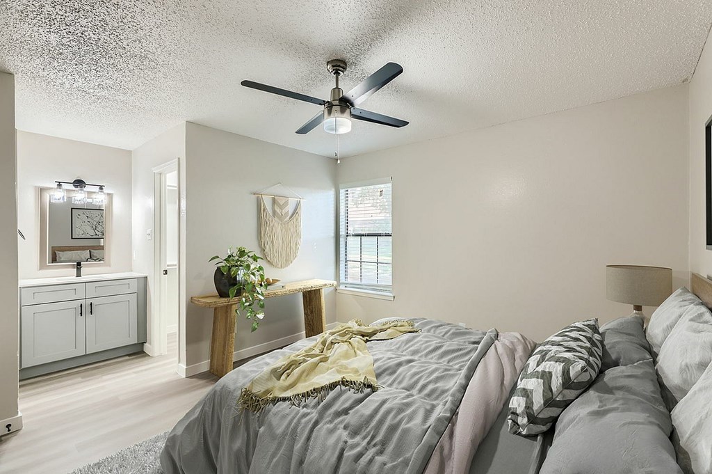 A bedroom with a bed, a ceiling fan, and a window.