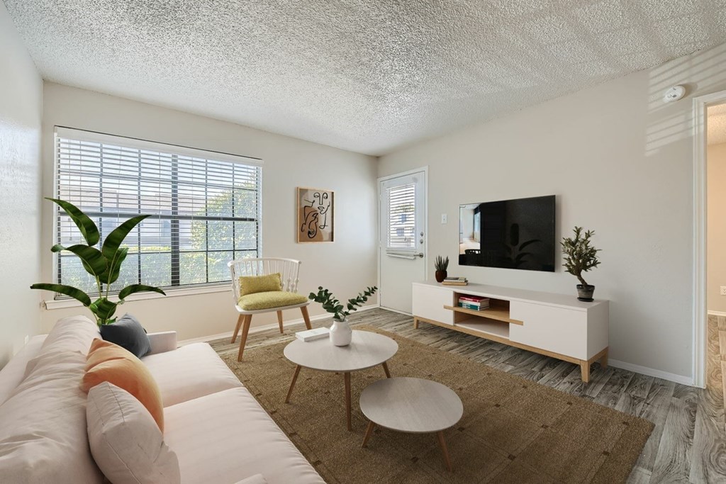 A living room with a white couch, a wooden coffee table, and a flat-screen TV.
