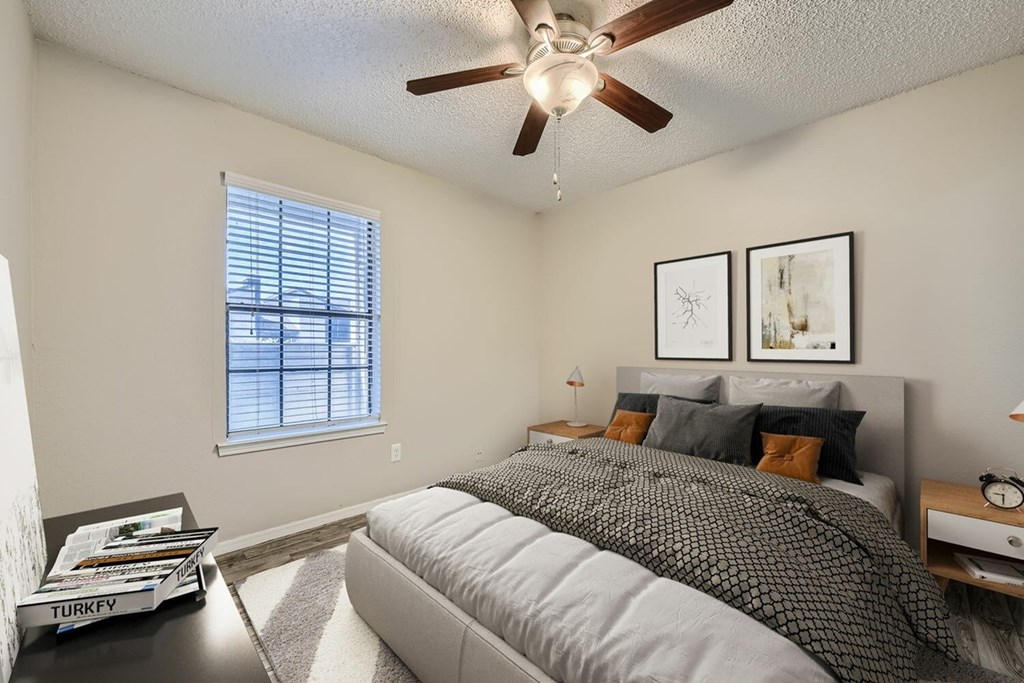 A bedroom with a bed, nightstand, and window.