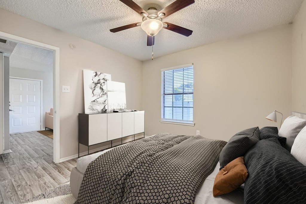 A bedroom with a large bed and a ceiling fan.