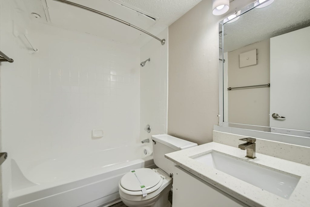 A white bathroom with a toilet, sink, and bathtub.