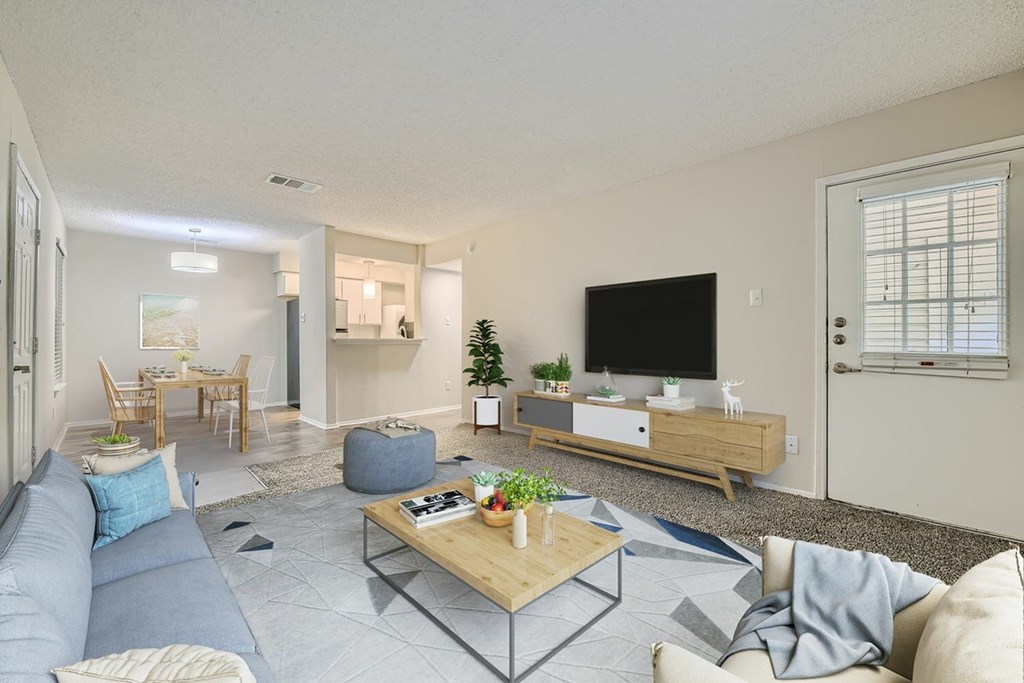 A living room with a grey sofa, a wooden coffee table, and a TV on a wooden stand.