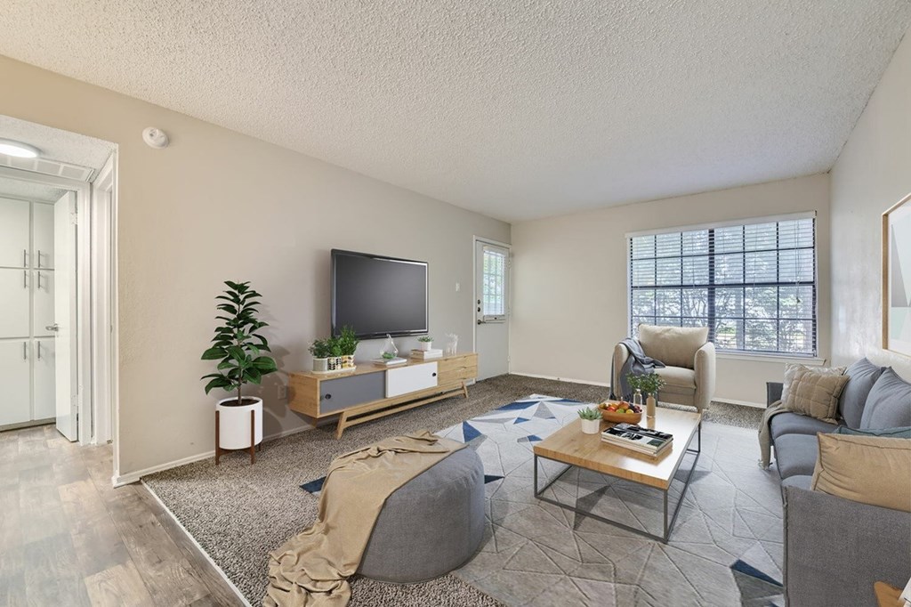 A living room with a grey couch, a wooden coffee table, and a flat screen TV.