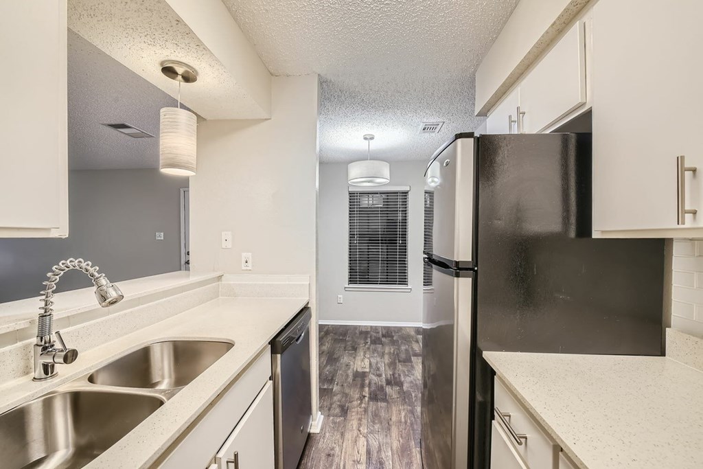 A kitchen with a black refrigerator and white cabinets.
