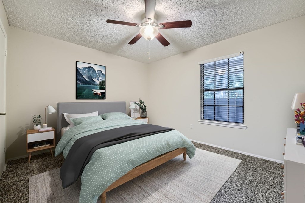 A bedroom with a bed, nightstands, and a window.