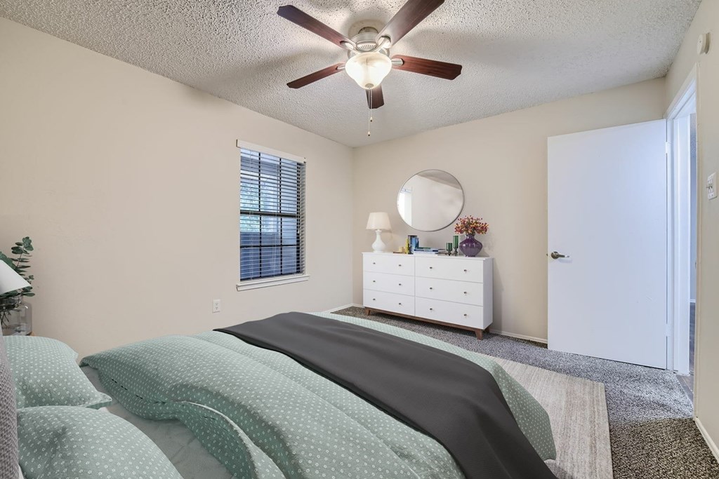 A bedroom with a bed, dresser, and window.