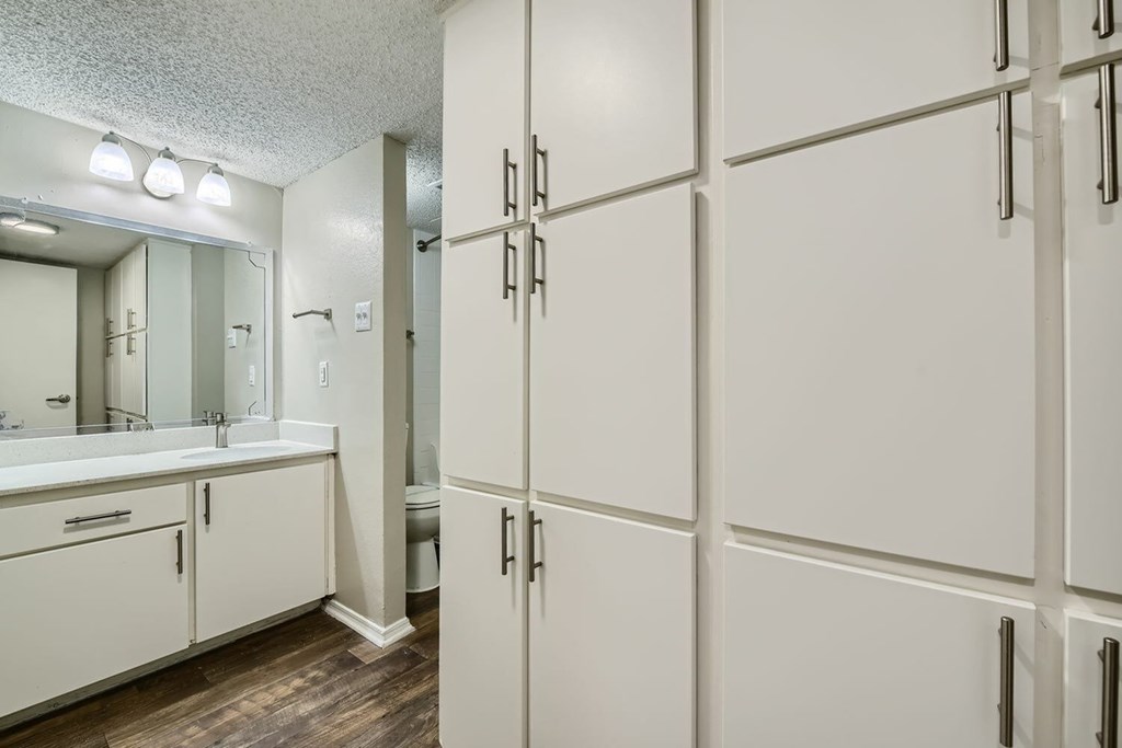 A bathroom with white cabinets and a mirror.