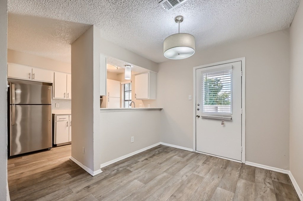 A kitchen with a stainless steel refrigerator and wooden flooring.