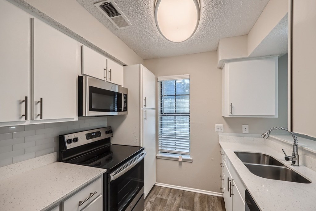 A kitchen with white cabinets and black appliances.