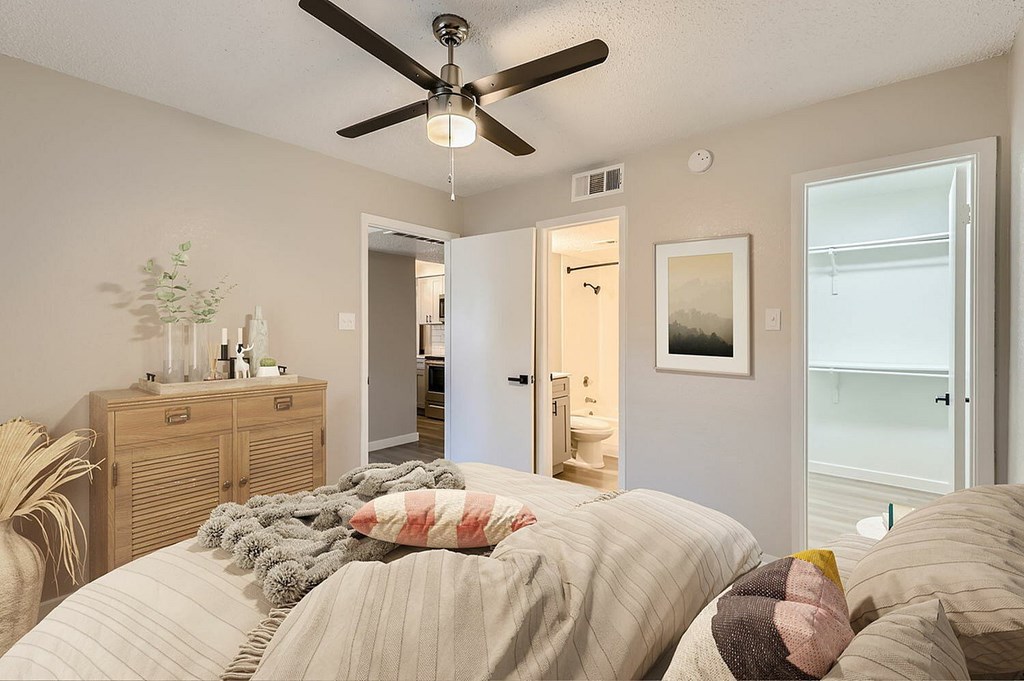 A bedroom with a bed, dresser, and ceiling fan.