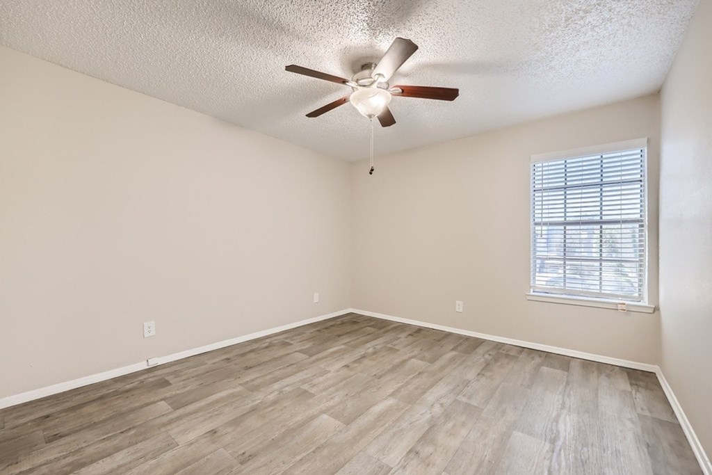 A room with a ceiling fan and a window with blinds.