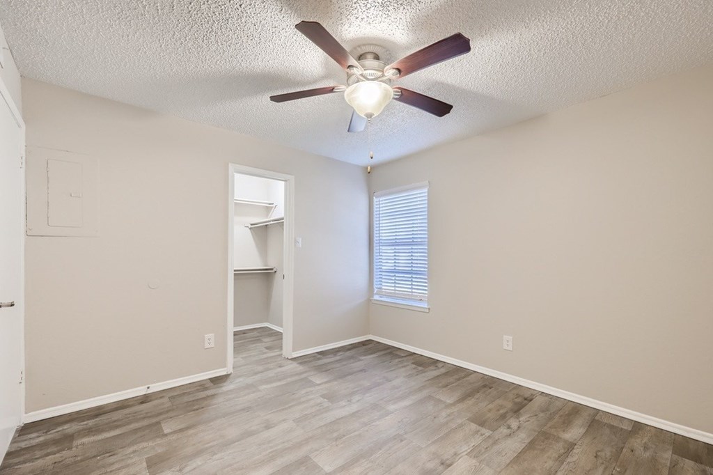 A room with a ceiling fan and wooden flooring.