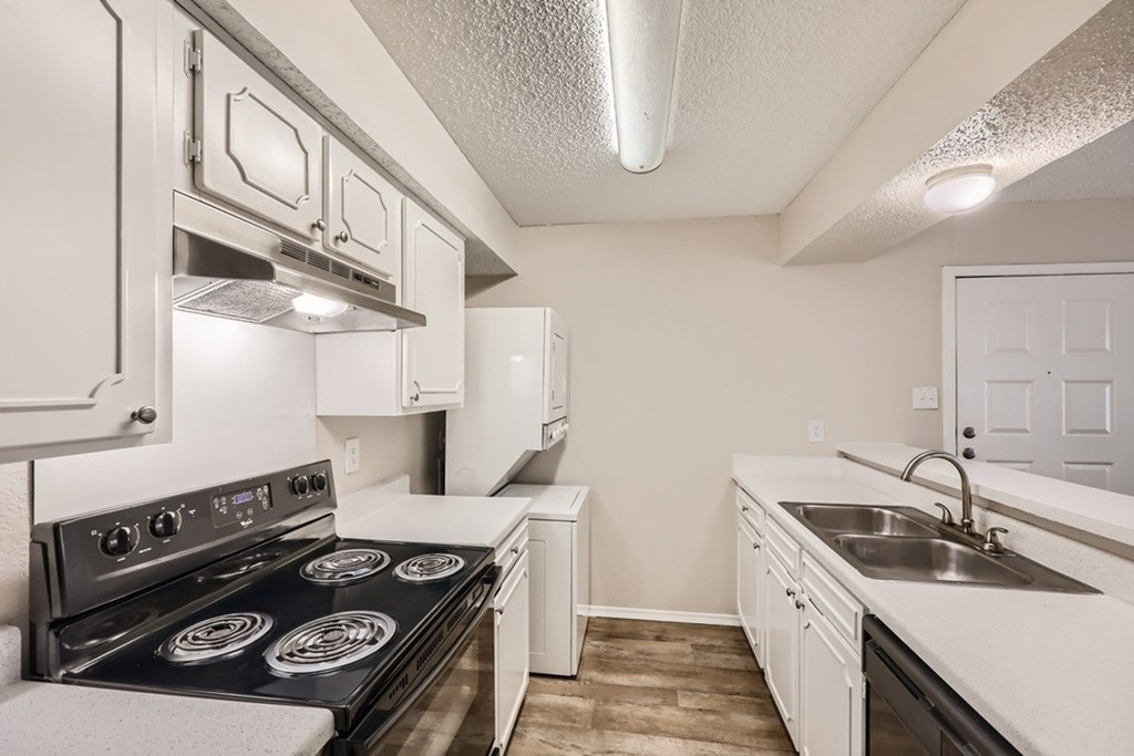 A kitchen with a black stove top oven and white cabinets.