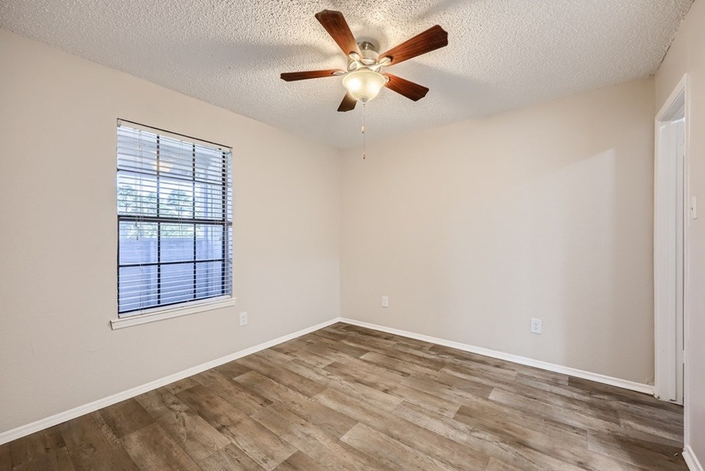 A room with a ceiling fan and a window with blinds.