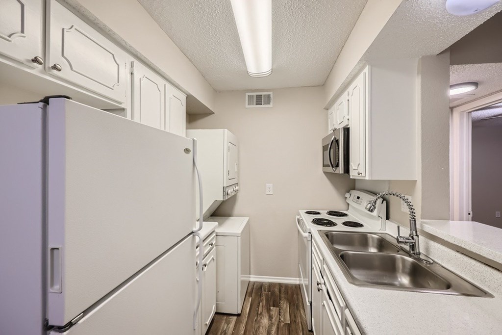 A kitchen with white appliances and cabinets.