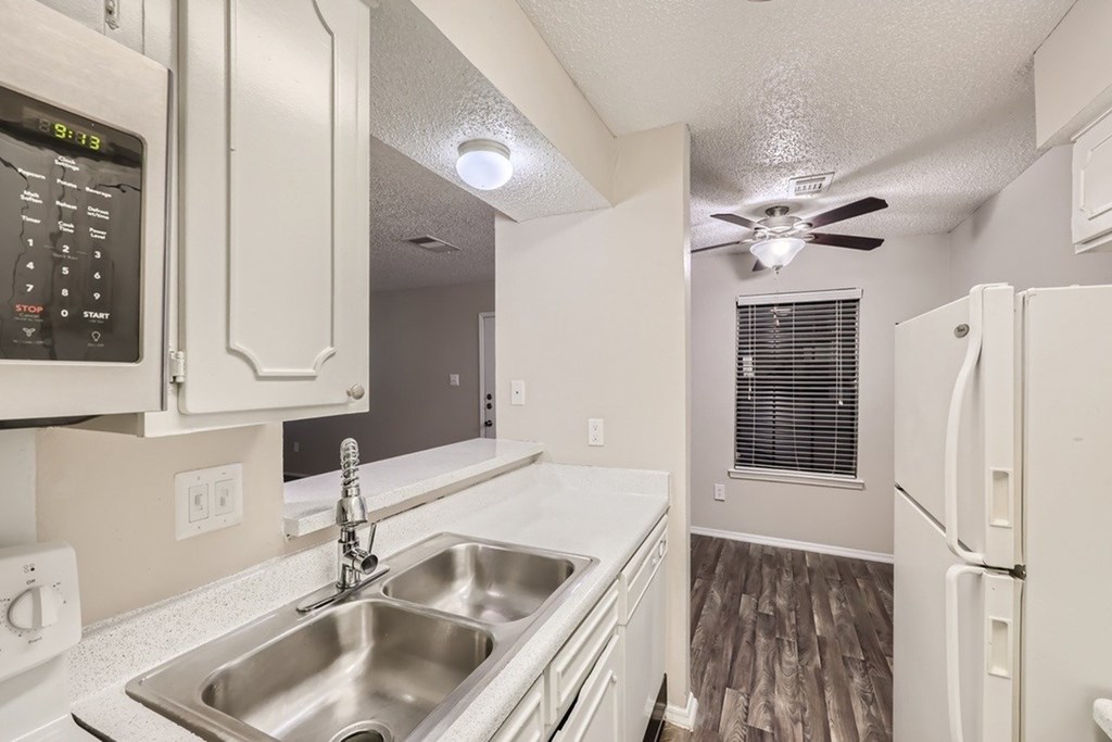 A kitchen with white appliances and a wood floor.