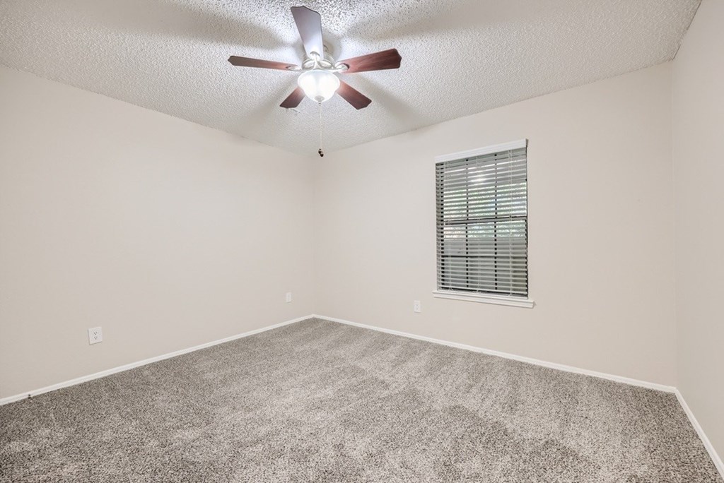 A room with a ceiling fan and a window with blinds.