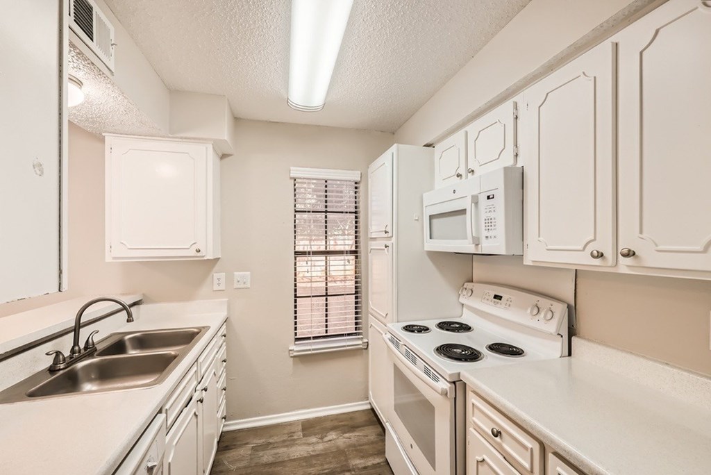 A kitchen with white cabinets and a stove top oven.