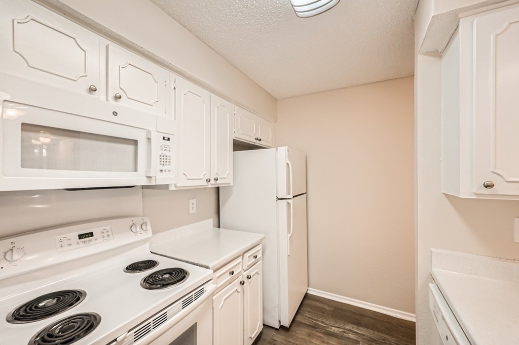 A white kitchen with a stove, microwave, and refrigerator.