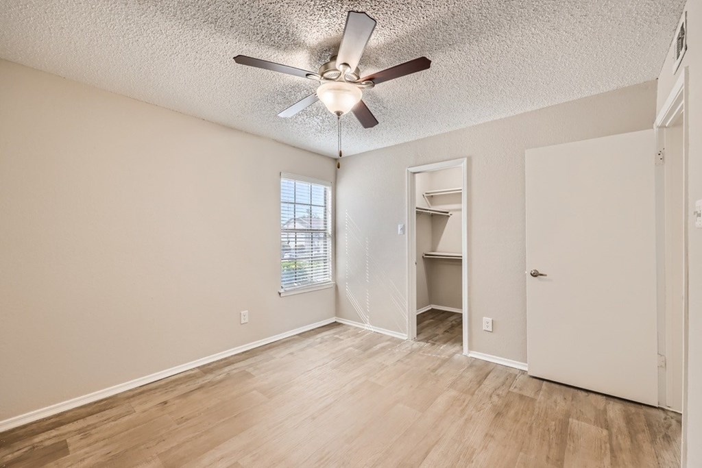 A room with a ceiling fan and a window with blinds.