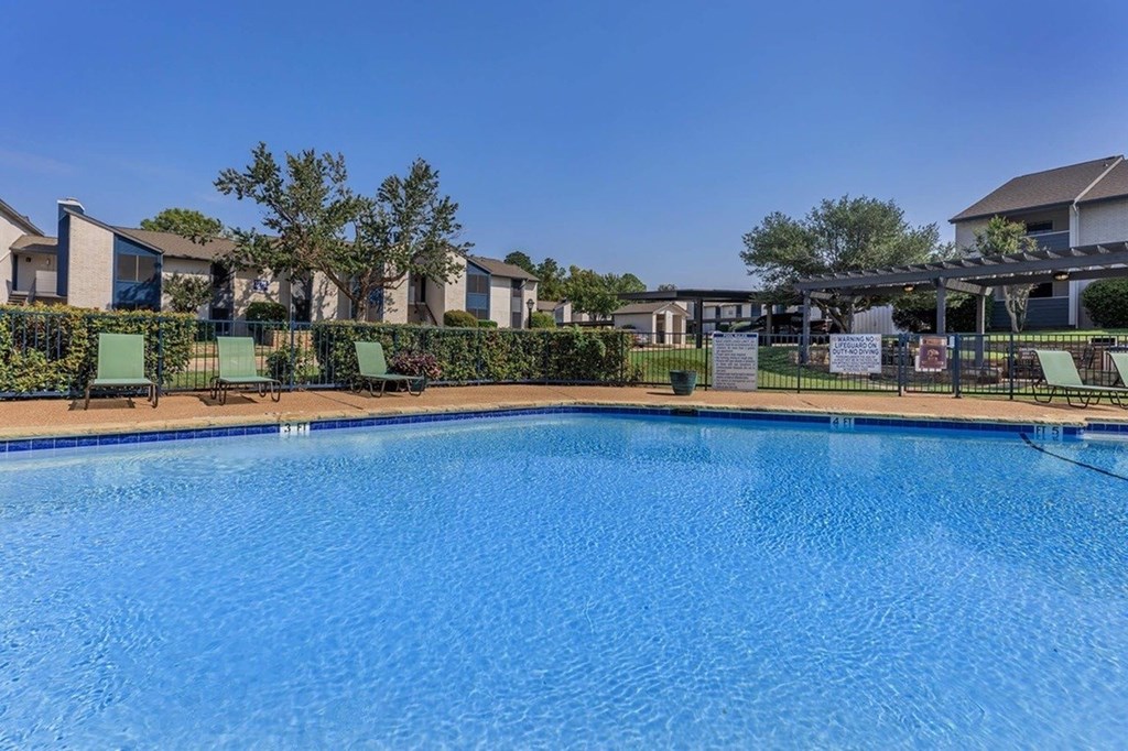 A large swimming pool in front of a building with a clear blue sky.