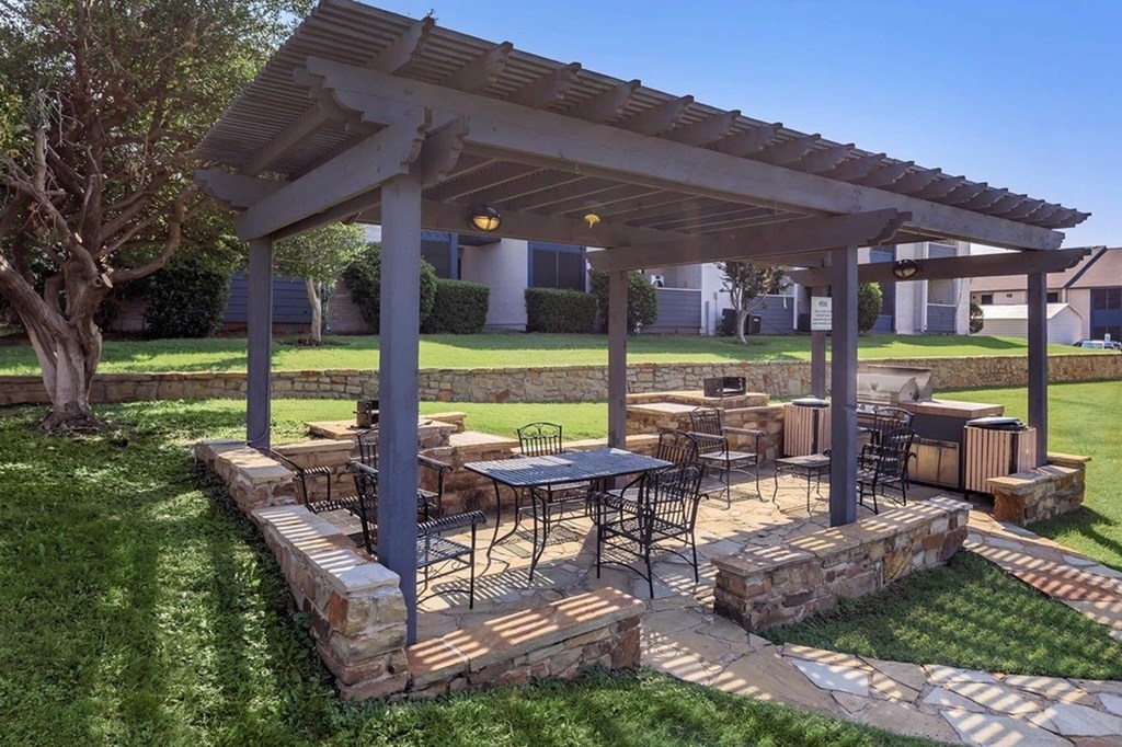 A patio with a table and chairs under a pergola.