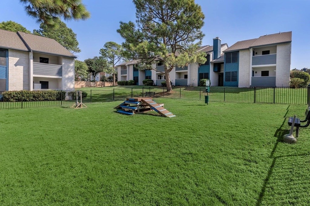 A grassy area in front of a building with a tree and a picnic table.