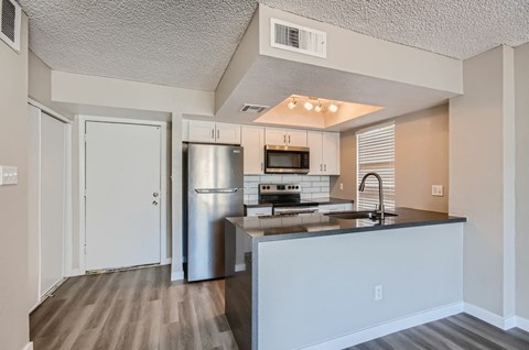 A kitchen with a refrigerator, microwave, oven, and sink.