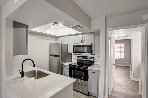 A kitchen with a stainless steel refrigerator, microwave, and oven.
