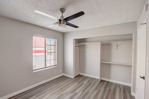 A room with a ceiling fan and a window with blinds.