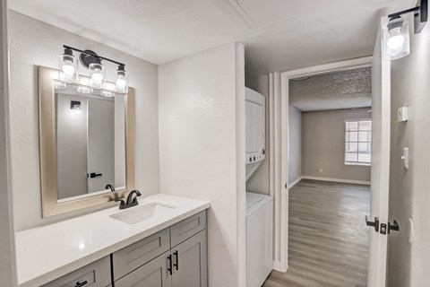 A bathroom with a sink, mirror, and lighting fixture.