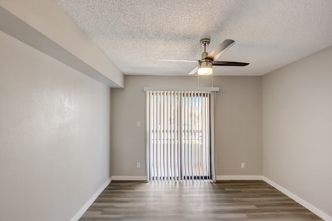 A room with a ceiling fan and a window with blinds.