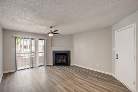 A living room with a fireplace and a ceiling fan.