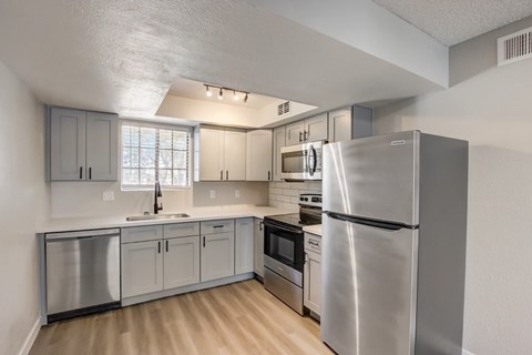A kitchen with stainless steel appliances and wooden floors.