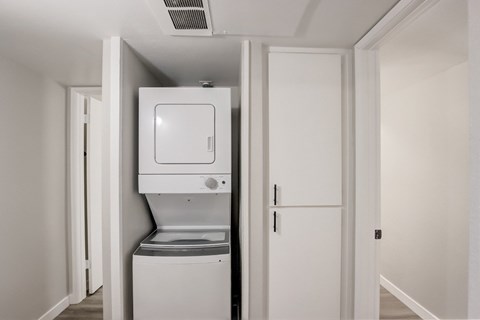 A white washing machine is in a small white room.