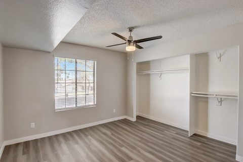 A room with a ceiling fan and a window with blinds.