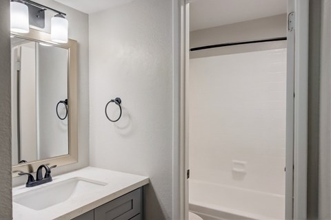 A bathroom with a sink, mirror, and towel rack.