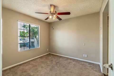 A room with a ceiling fan and a window with blinds.