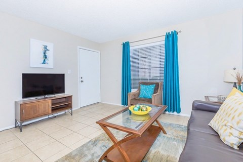 A living room with a grey couch, a wooden coffee table, and a television on a cabinet.