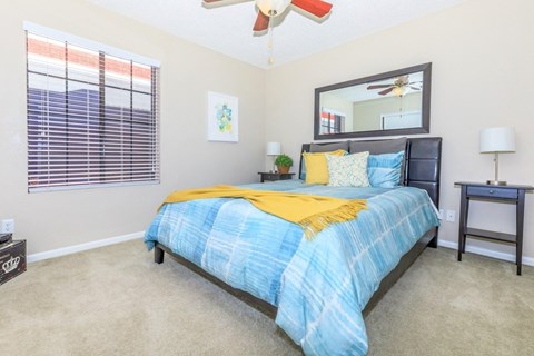 A bedroom with a bed, a ceiling fan, and a small table.
