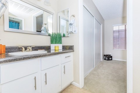 A bathroom with a sink, mirror, and white cabinets.